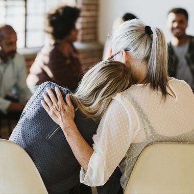 Two women hugging during group therapy
