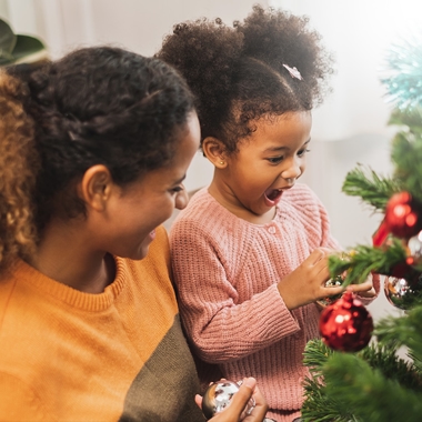 Mother and daughter hanging holiday ornaments