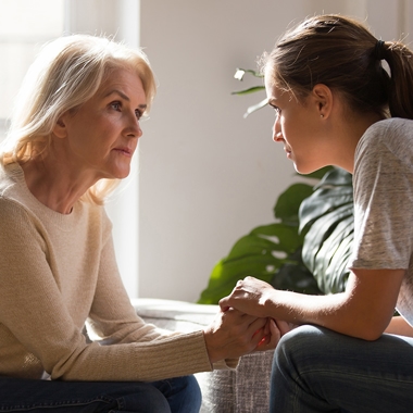 Mother having a serious conversation with her daughter while holding hands.