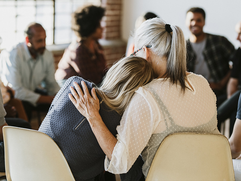 Two women hugging during group therapy