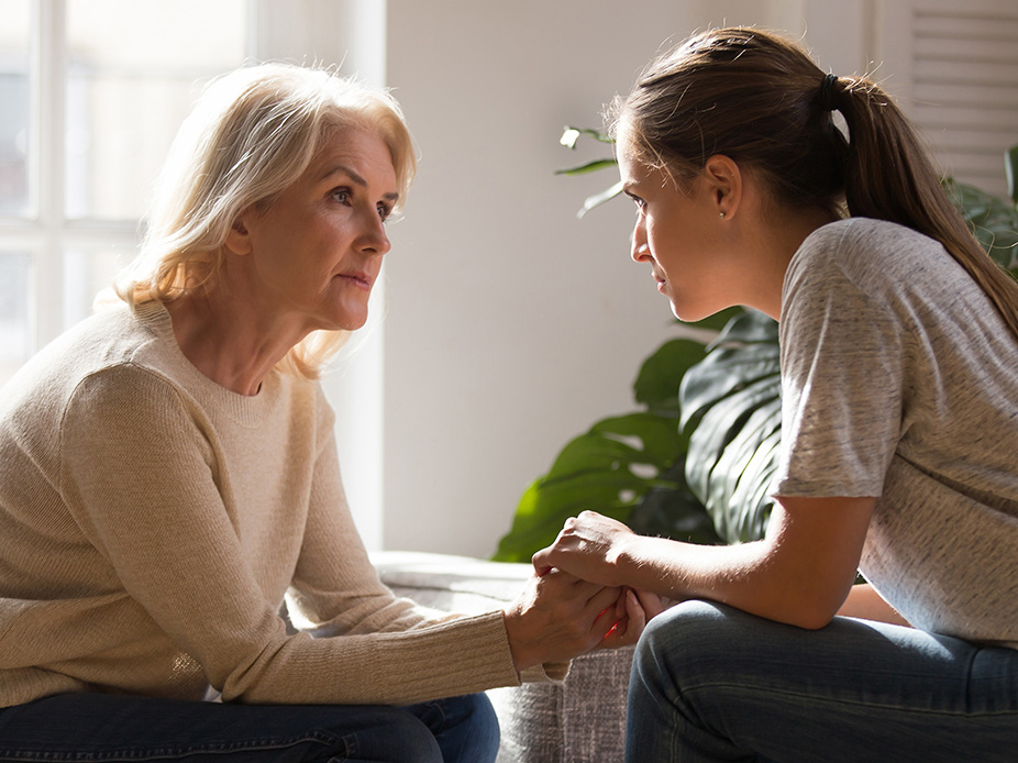Mother having a serious conversation with her daughter while holding hands.